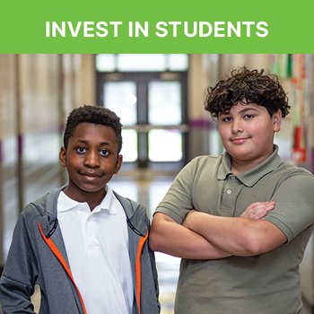 2 children, one of them folding their arms and the other with their hands in their jacket, in a school hallway smiling