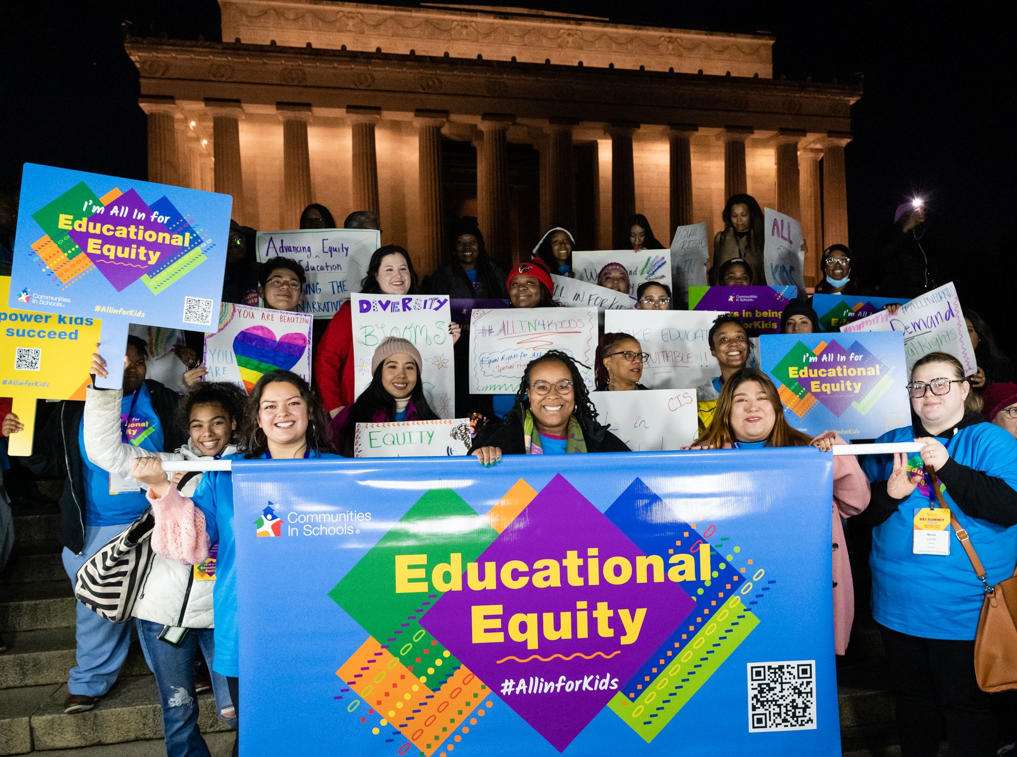 CIS alumni in front of the Lincoln Memorial with "All in for educational equity" signs