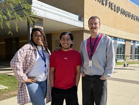 Two CIS site coordinators standing outside of school with CIS student